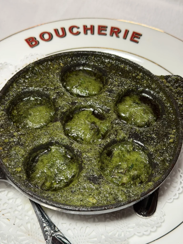 Close-up of six escargots bubbling in green herb butter