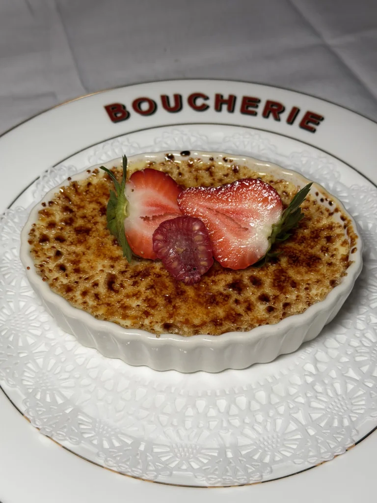 Vanilla creme brulee with torched sugar crust and fresh strawberries