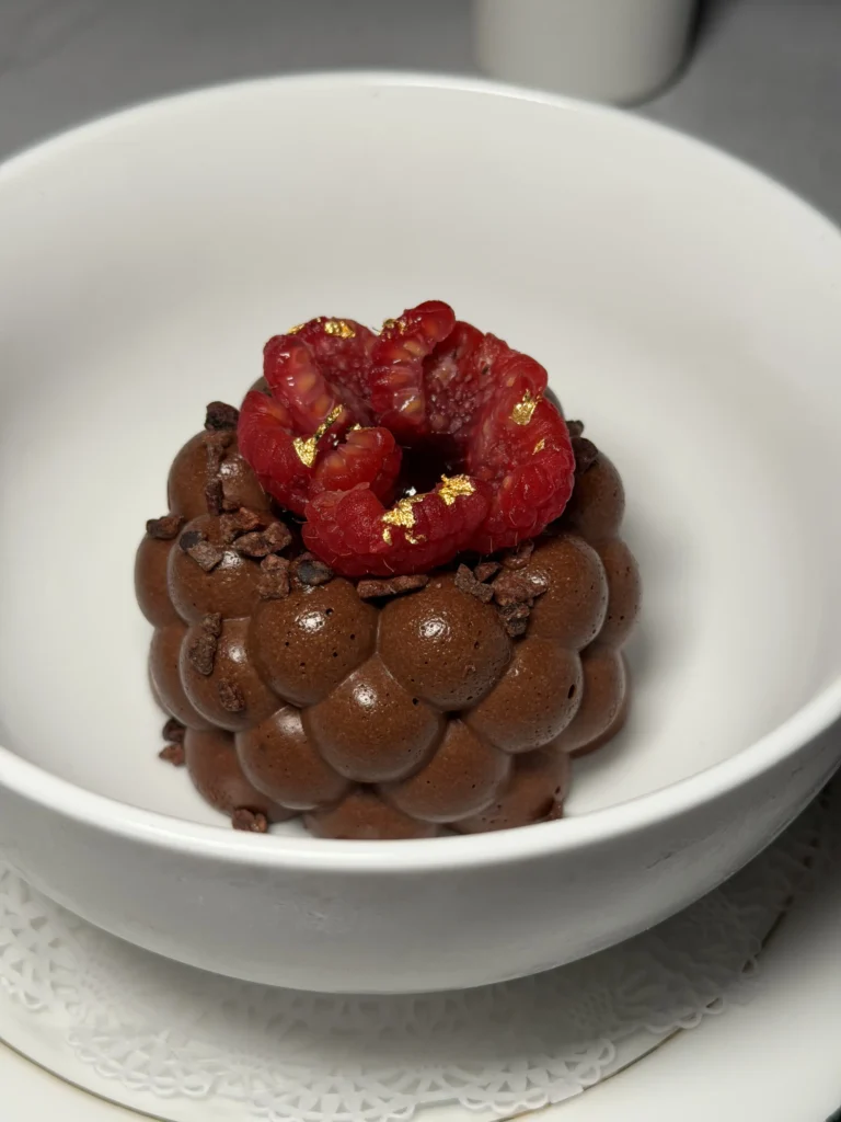 Valrhona chocolate mousse dome with raspberries and gold leaf