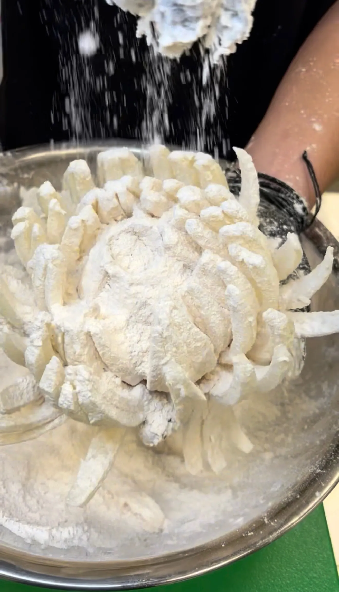 Blooming onion coated in seasoned flour during preparation