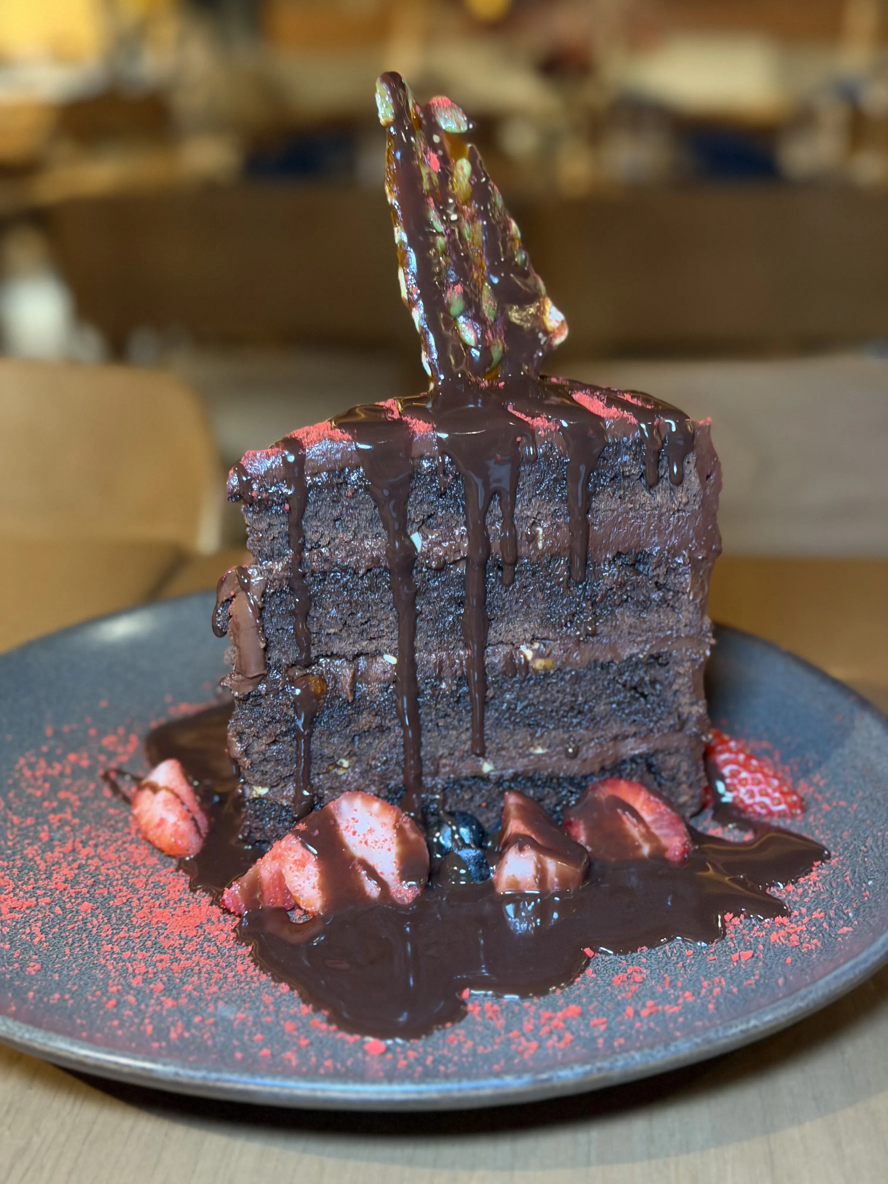 Dark chocolate cake slice with strawberries and dripping chocolate sauce