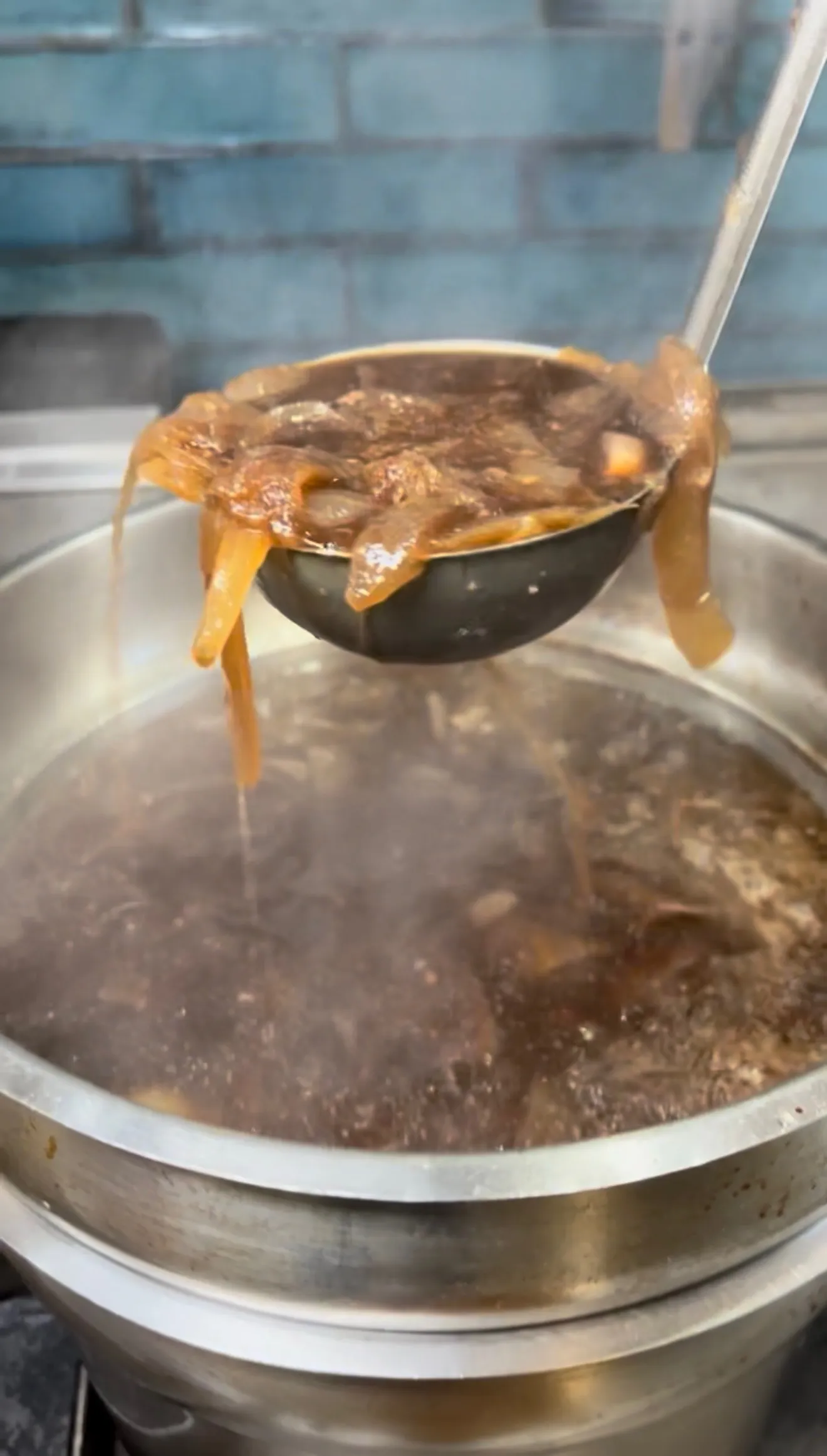 Ladle lifting French onion soup with melted cheese dripping
