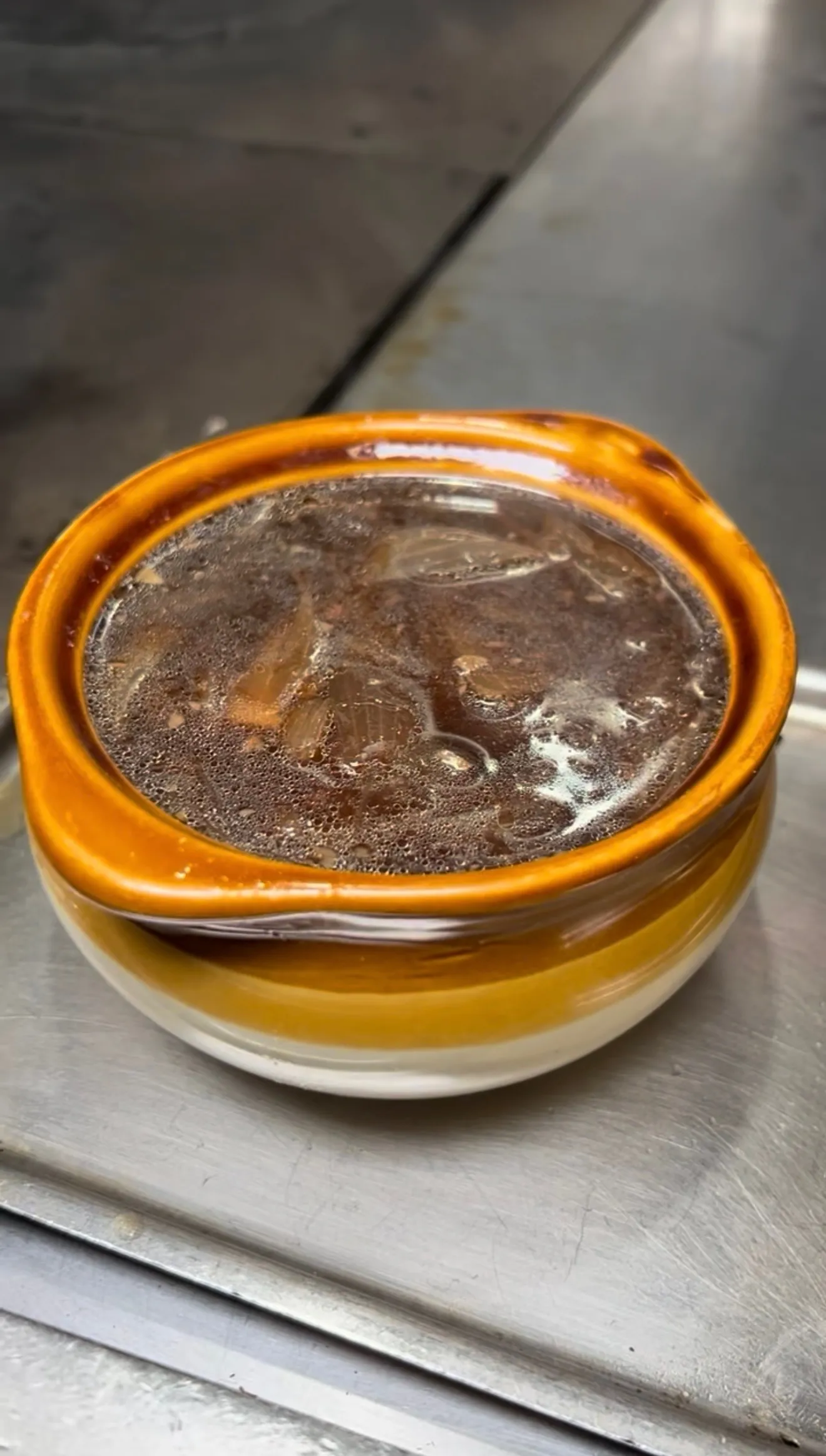 French onion soup in a ceramic crock with melted cheese on top