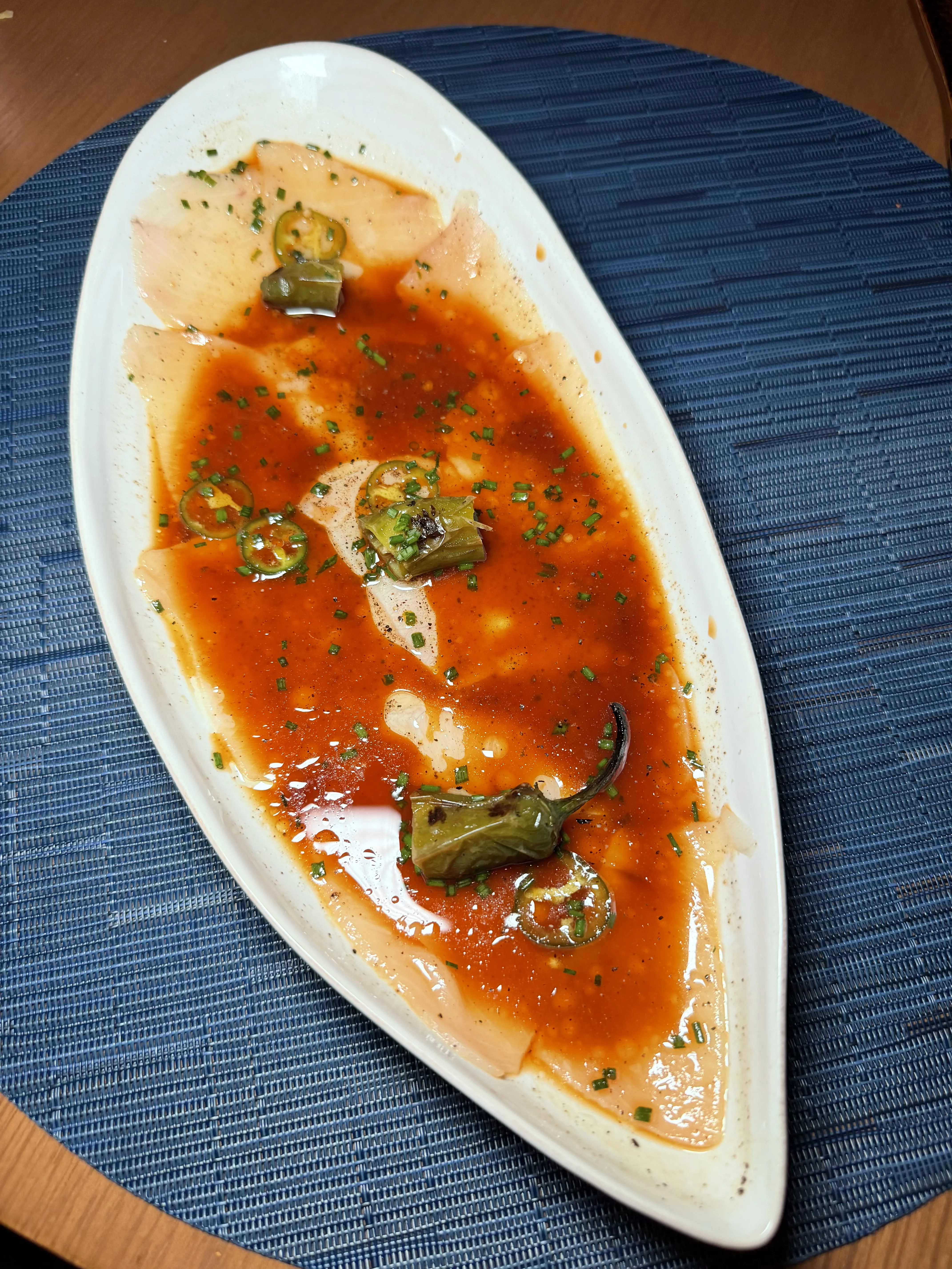 Hamachi sashimi with serrano, truffle oil, and yuzu on elegant plating