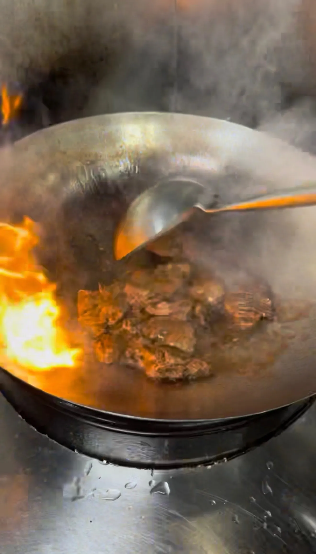 Lomo saltado beef searing in wok with visible flames