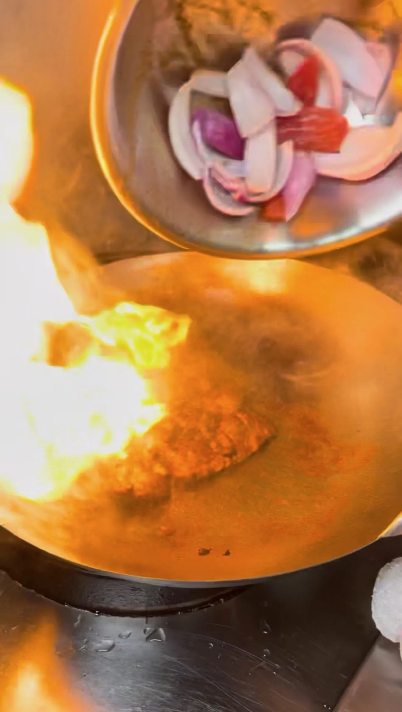 Lomo saltado cooking in wok with flame from high heat