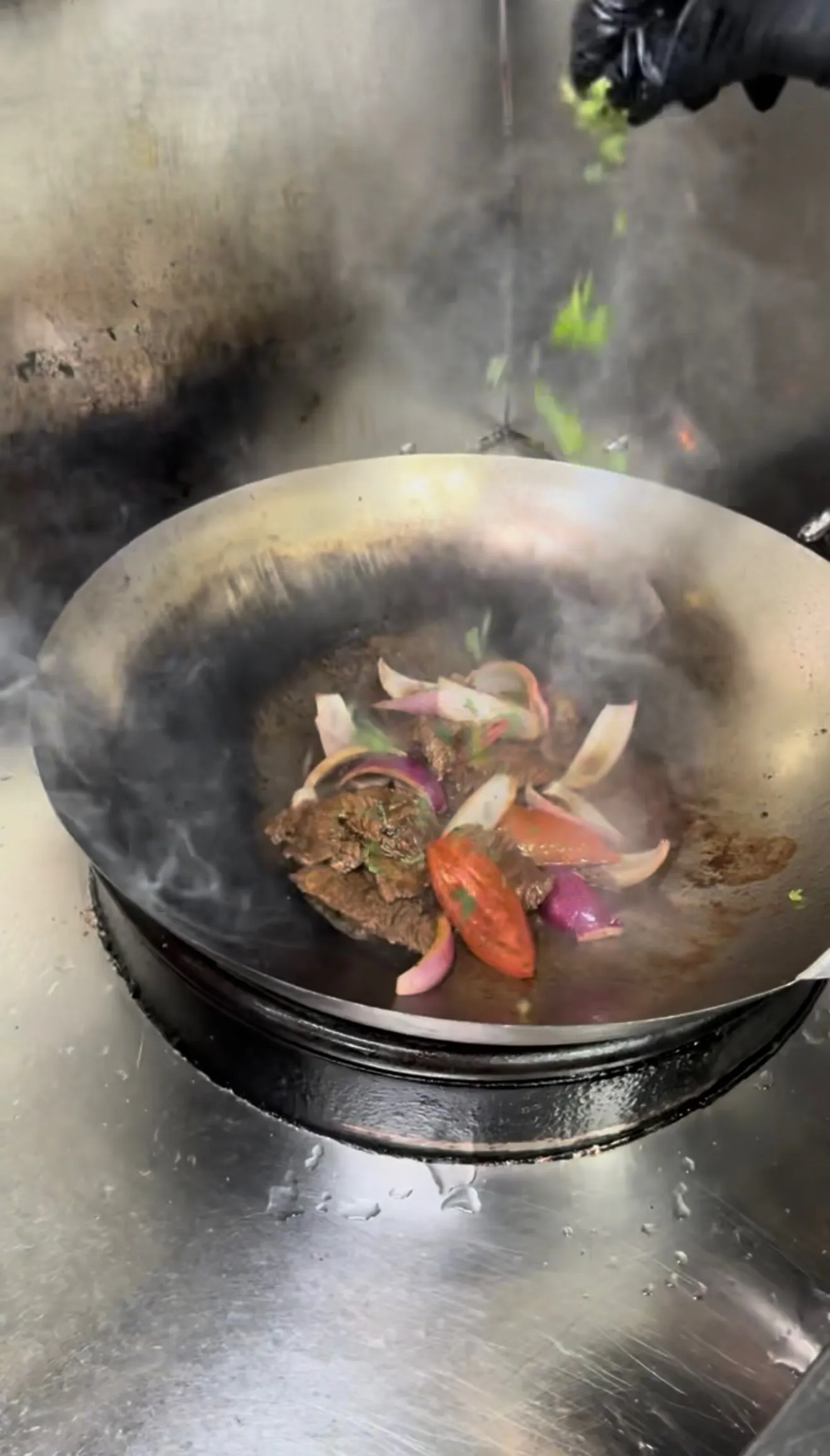 Lomo saltado vegetables cooking in wok with steam rising