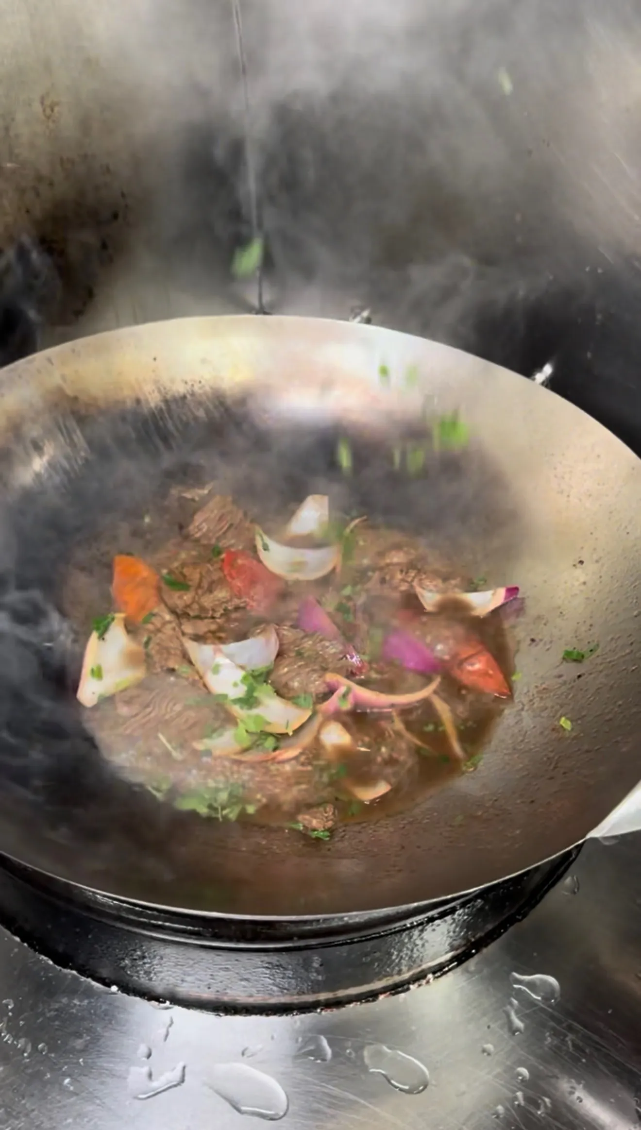 Lomo saltado sizzling in wok with steam rising