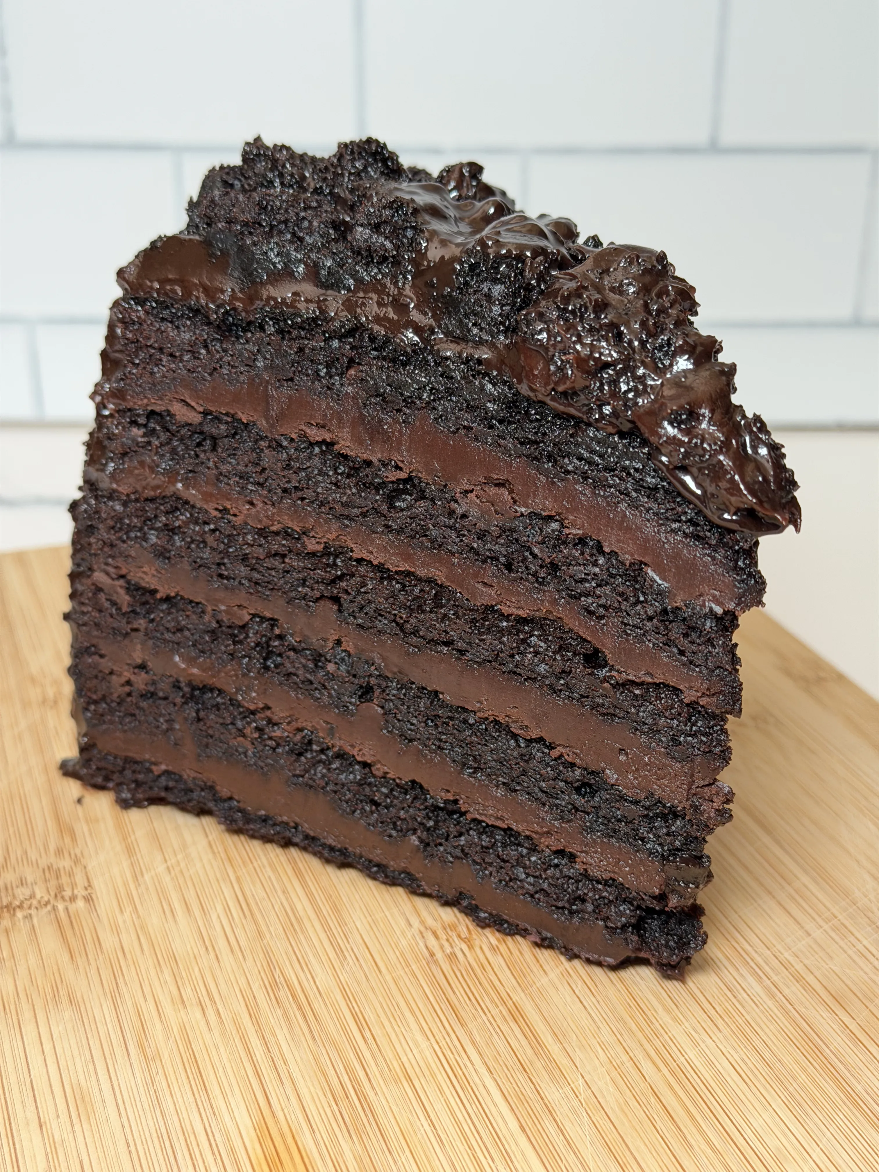 Slice of Great Wall of Chocolate cake on a wooden board showing dense layers