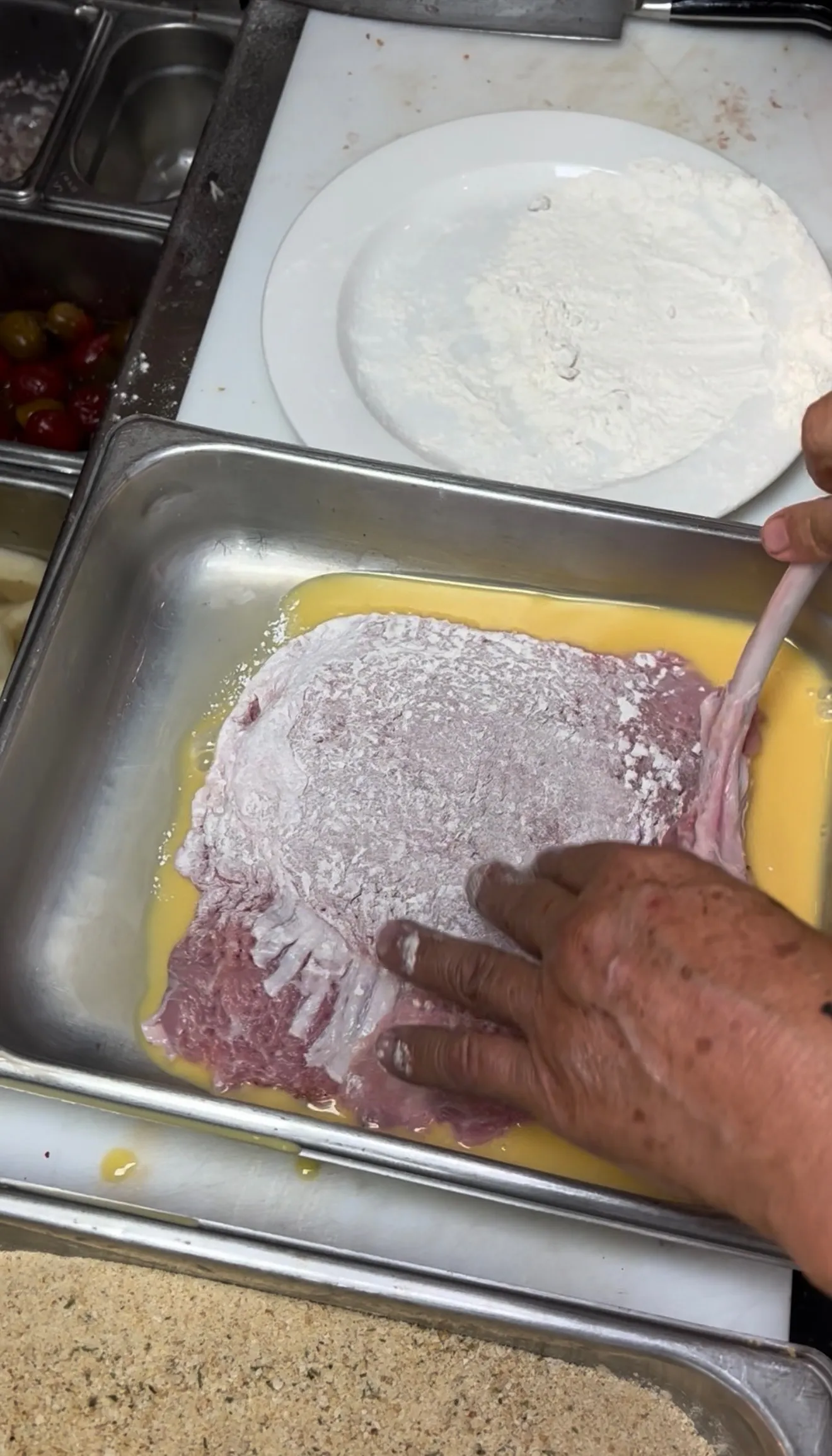 Veal chop coated in flour during kitchen preparation