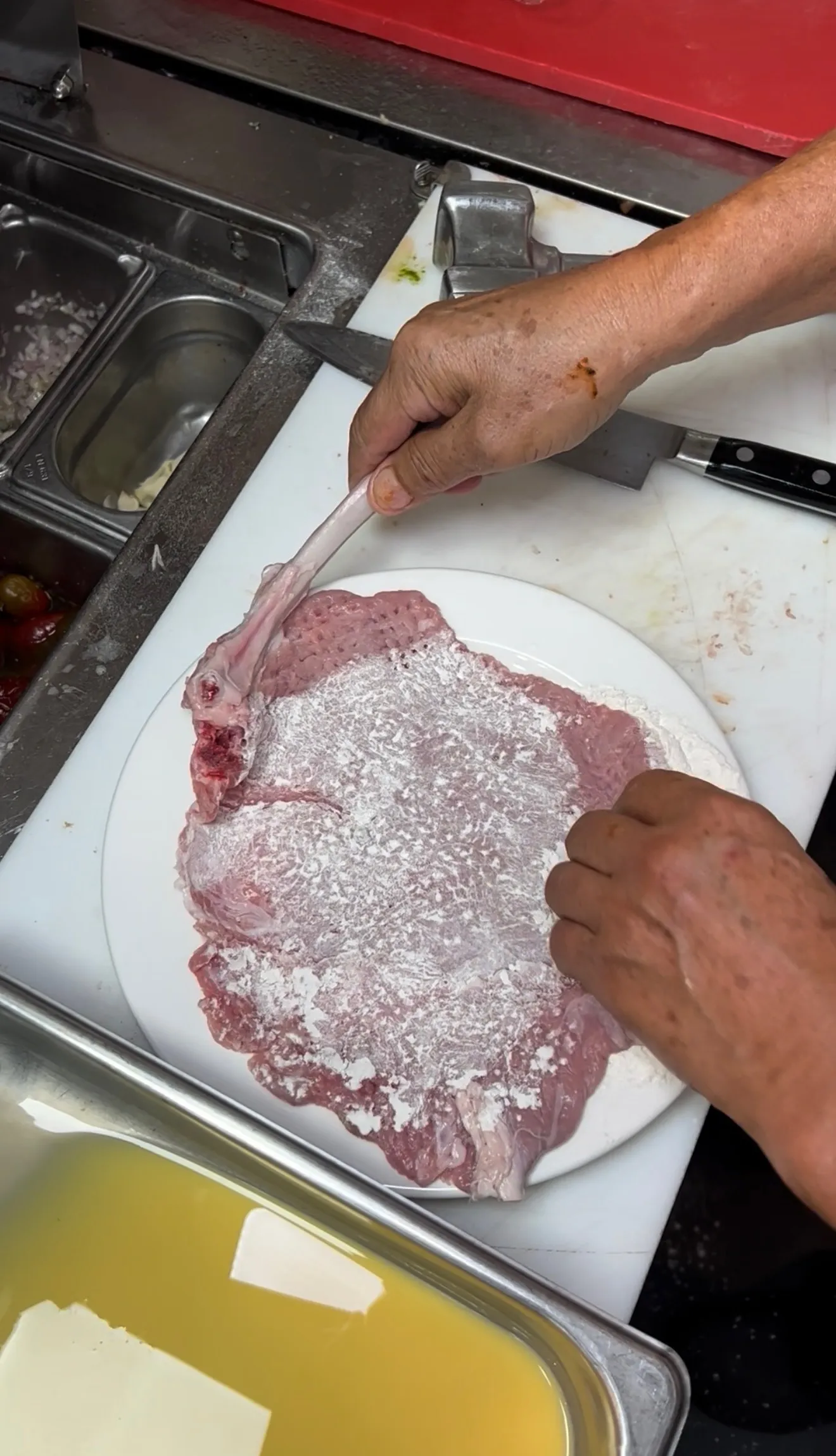 Veal chops being dredged in flour for parmigiana breading