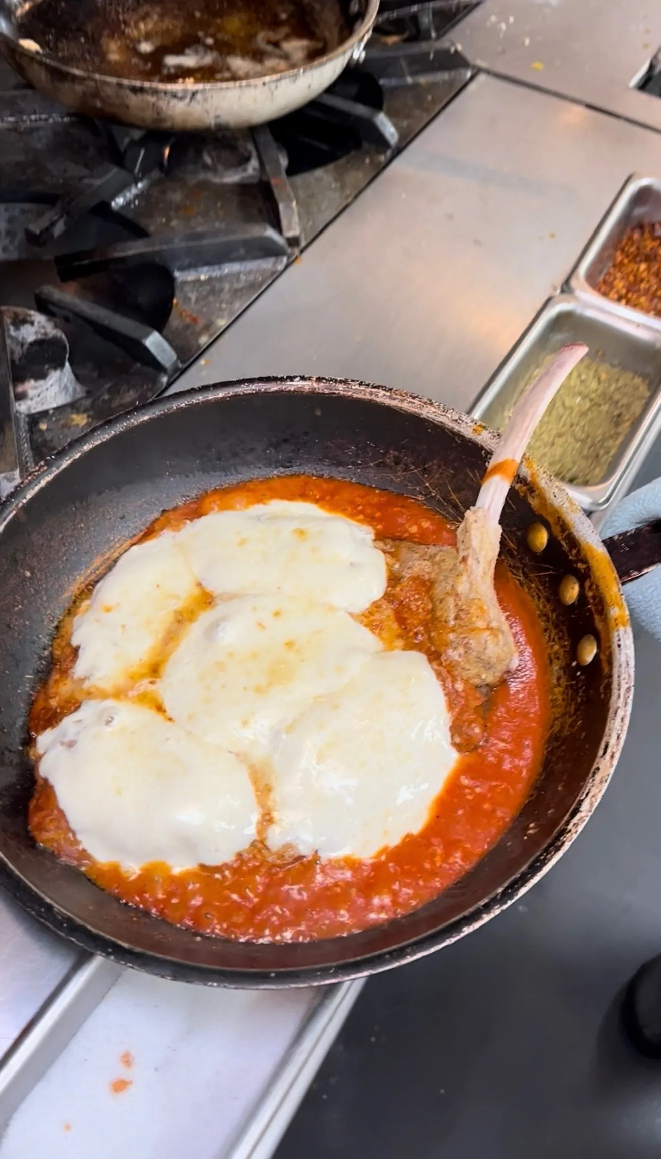 Veal parmigiana with melting mozzarella and tomato sauce in a baking pan