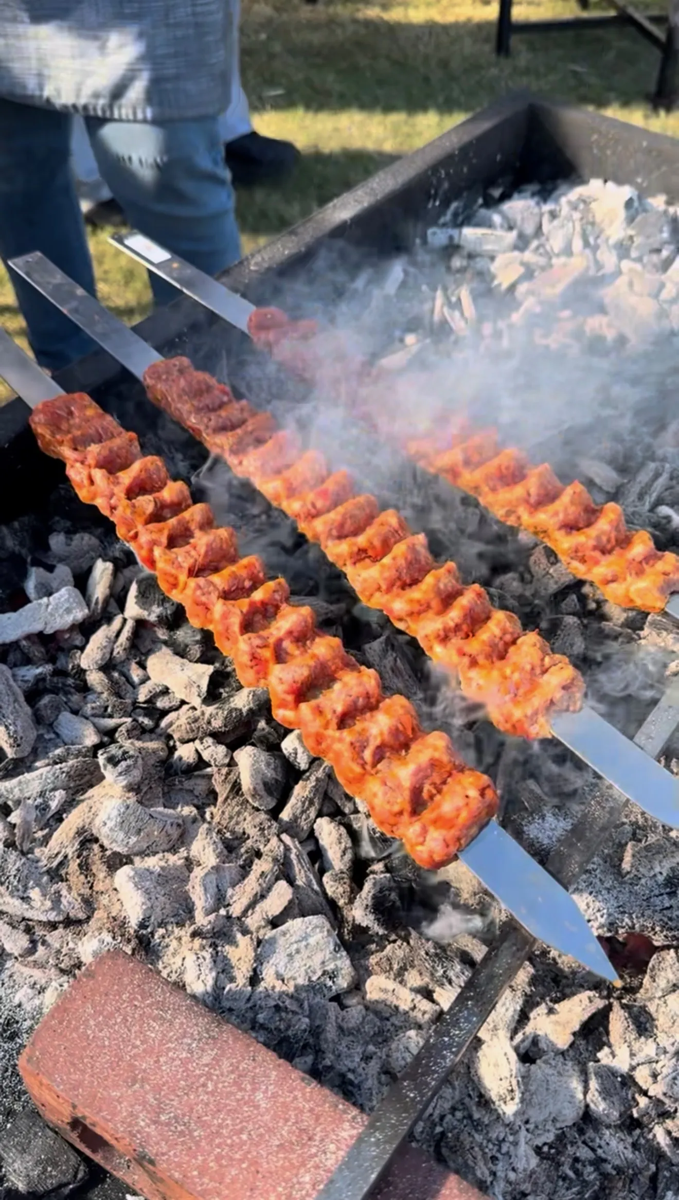 Authentic Adana kebab skewers grilling over hot charcoal with smoke rising from the barbecue