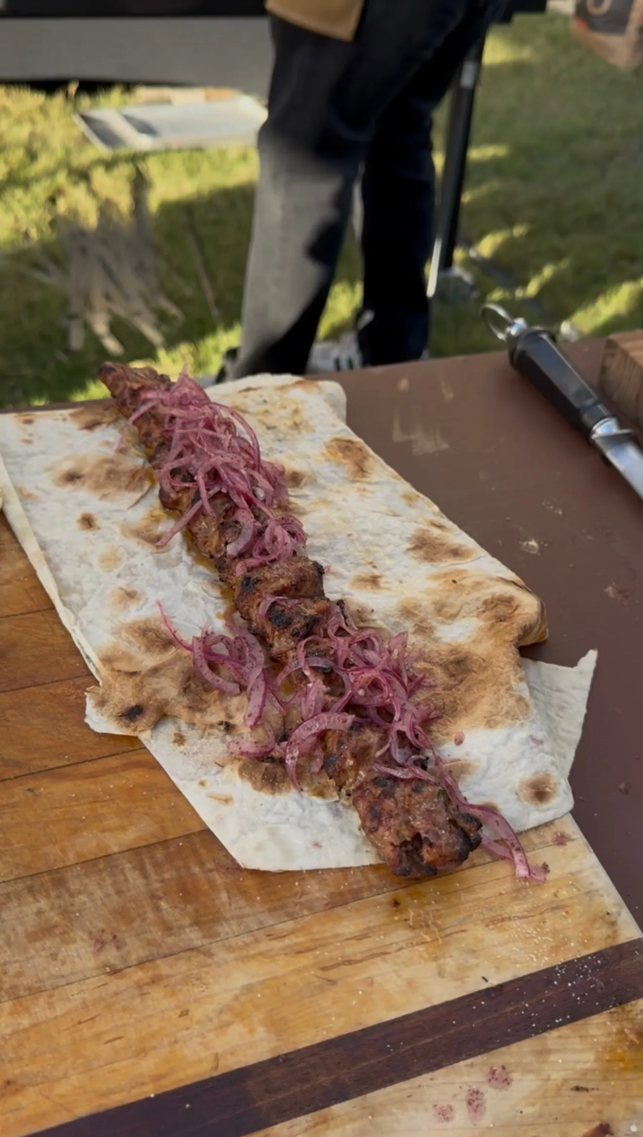 Authentic Adana kebab served on flatbread with pickled onions