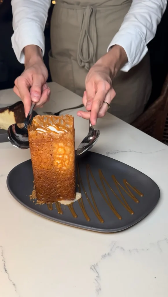 Chef plating Bananas in a Box dessert with caramel sauce on black plate using professional technique