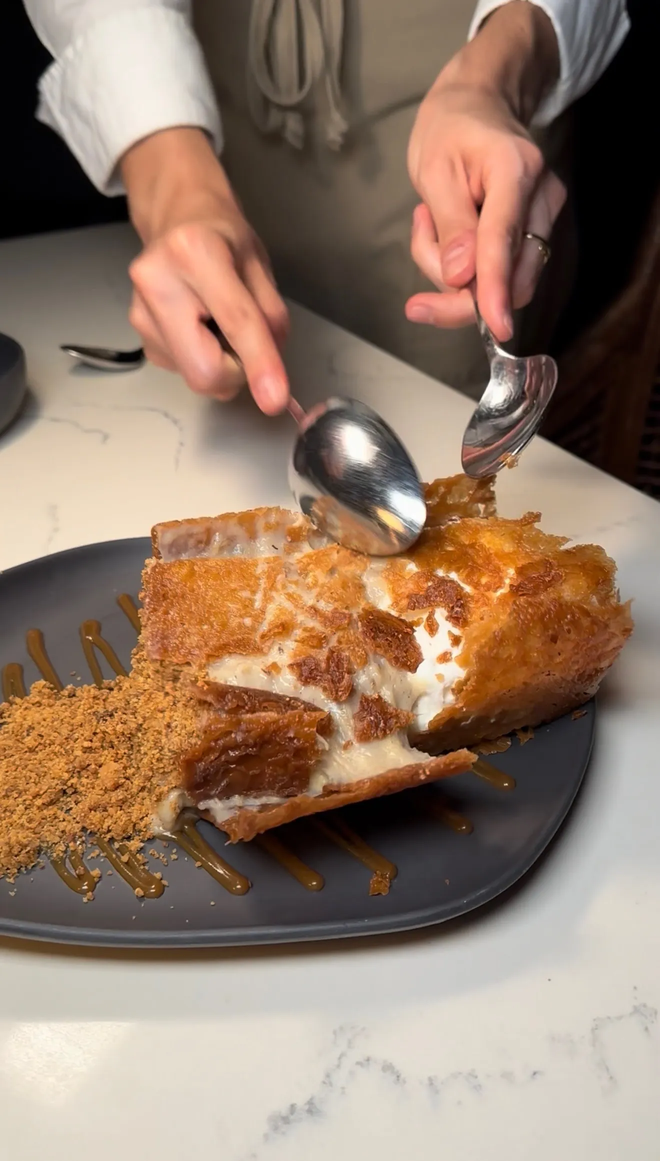 Chef plating Bananas in a Box dessert with caramelized honeycomb and cream filling on dark plate