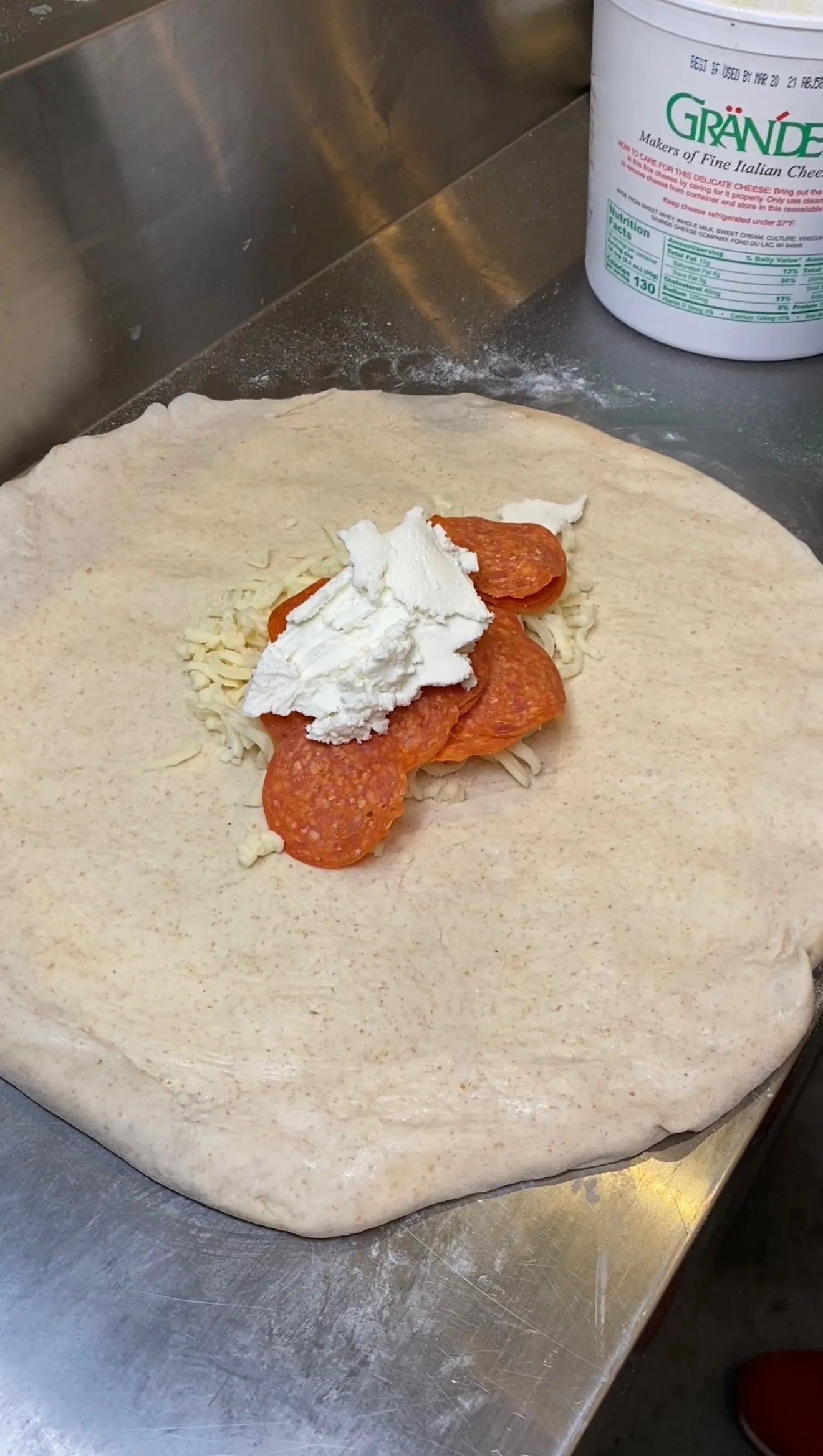 Raw pizza dough with pepperoni ricotta and shredded cheese filling ready to be folded