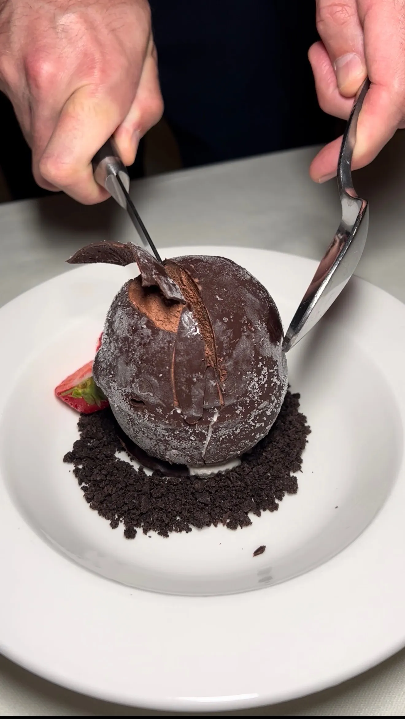 Chocolate shell tartufo being cracked open revealing the dessert interior