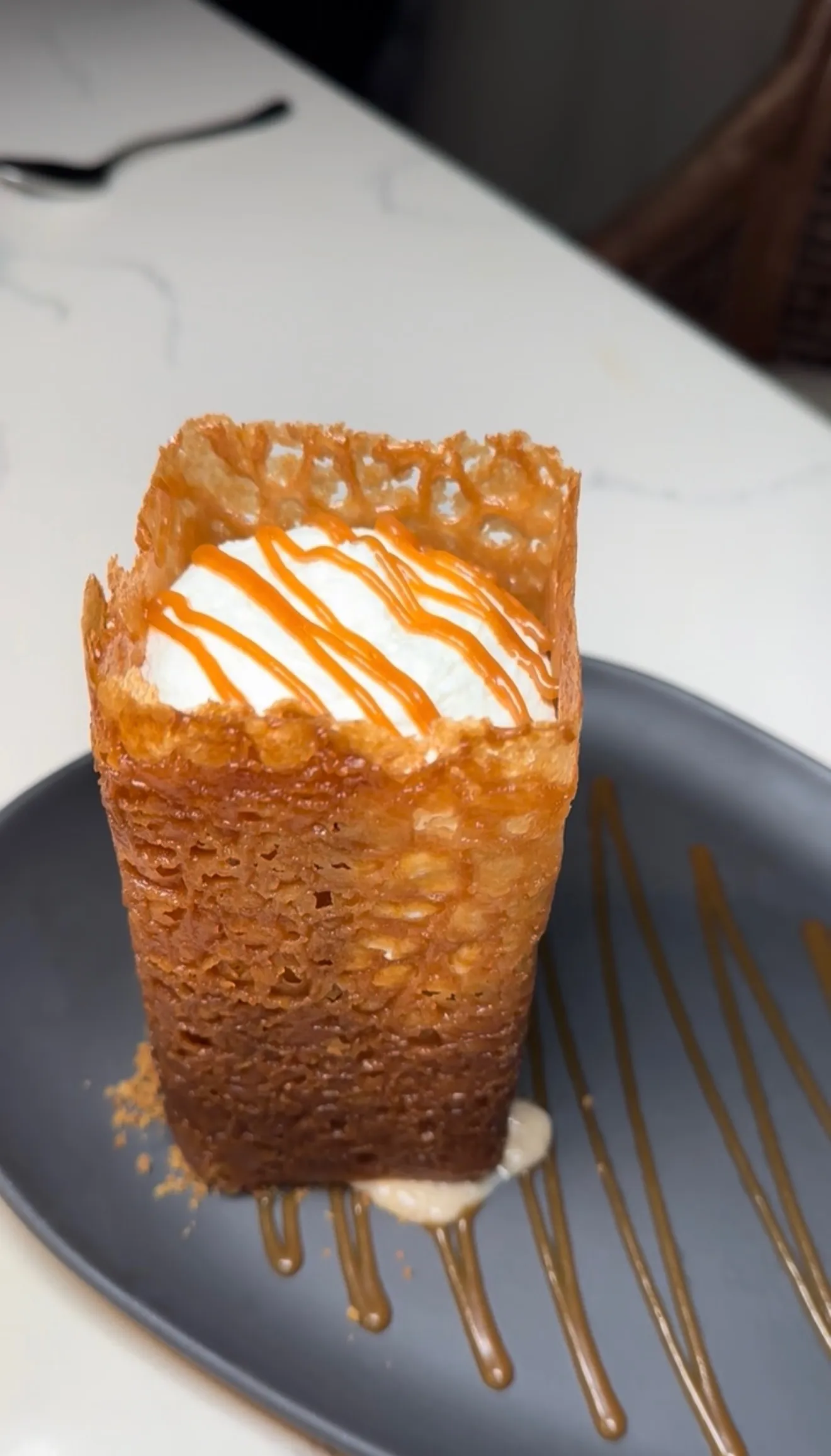 Crispy pastry cup with whipped cream and caramel drizzle